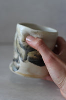 White and black painted wobble cup